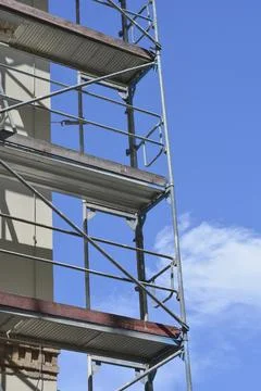 Construction scaffolding on a building facade against blue sky Stock Photos