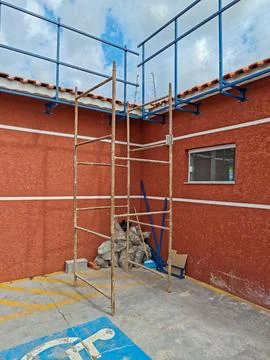 Construction scaffolding next to a red wall. Stock Photos
