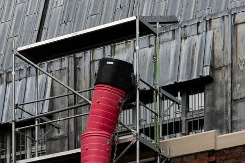 Construction scaffolding with red construction debris pipe at worksite Stock Photos
