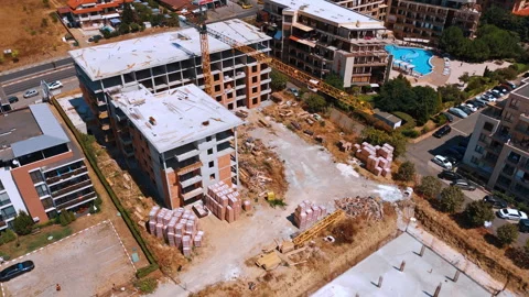Construction scene with stacked materials and crane. Building frames rise above Stock Footage 321538604