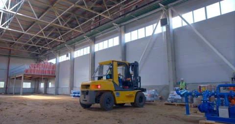 In a construction shop under construction, forklift unloads industrial equipment Stock Footage 161983914