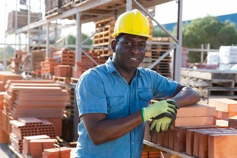 Construction shop worker stacks bricks on an open air site at summer day 写真素材
