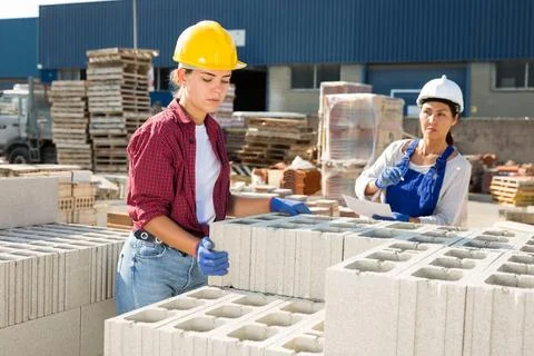 Construction shop worker stacks bricks on an open-air site Stockfoto's