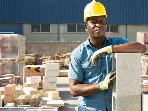 Construction shop worker stacks bricks on an open air site at summer day 写真素材