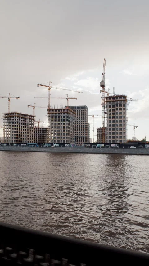 Construction site across river with cranes and iron fence in foreground 動画素材 318199807