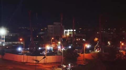 Construction site active at night, heavy drilling equipment working under bright Stock Footage 340963339