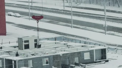 Construction site activity on snowy winter day, crane lifting pre-fabricated Video stock 323913257