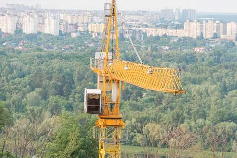 A construction site amidst a city backdrop, featuring a large yellow crane .. Stock Photos