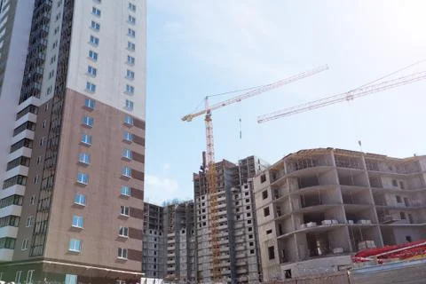 Construction site background. Hoisting cranes and new multi-storey buildings. Stock Photos