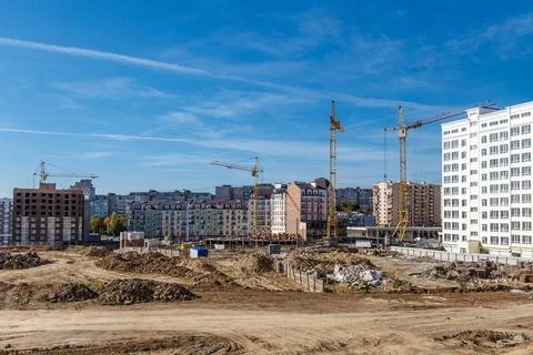 Construction site background. Hoisting cranes and new multi-storey buildings. Stock Photos