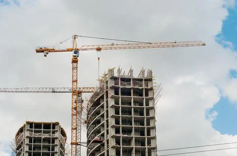 Construction site background. Hoisting cranes and new multi-storey buildings. Stock Photos