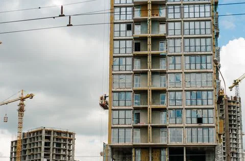 Construction site background. Hoisting cranes and new multi-storey buildings. Stock Photos