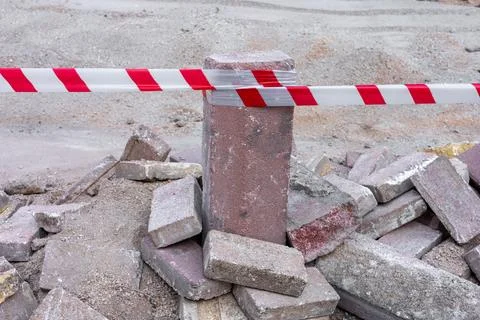 Construction site barrier with caution tape near piled bricks and stones at a Stock Photos