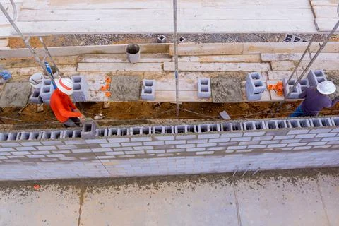 The construction site is being worked on by workers who are laying masonry Stock-Fotos