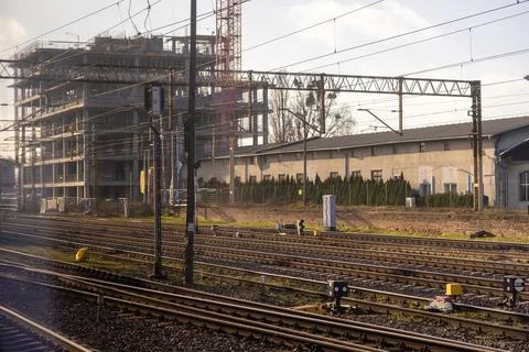 A construction site beside active train tracks displays a modern high-rise Stock Photos