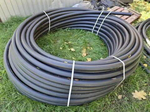 On the construction site, the black plastic pipe is coiled in a bundle Stock-Fotos