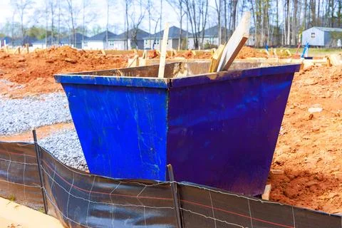 Construction site blue dumpster filled with waste near new housing developmen Stock Photos