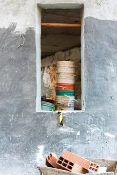 Construction site, bricks in wheelbarrow, stack of buckets in unfinished room Stock Photos