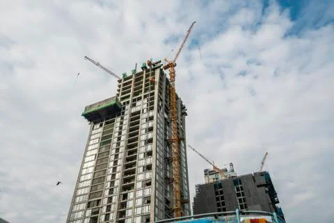 Construction site of building a high-rise building with a cranes against blue Stock Photos