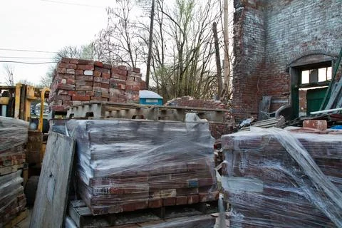 Construction Site Chaos with Bricks on Pallets and Forklift in Open Building Foto stock