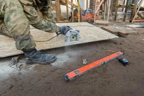 Construction Site. Construction worker with electrical circular saw saws the Stock Photos