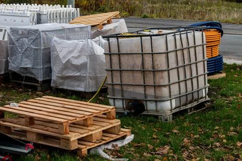 Construction site with containers and pallets near a road Stock Photos