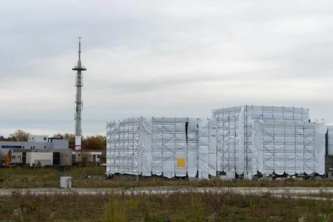 Construction site with covered structures near communication tower Stock Photos