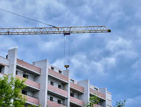 Construction site. Crane and multi-storey brick house against the blue sky. Stock Photos