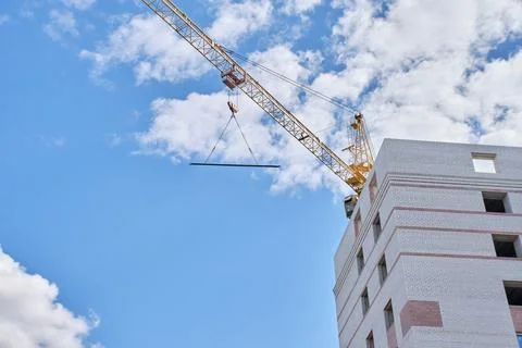 Construction site. Crane and multi-storey brick house against the blue sky. Stock Photos