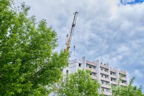 Construction site. Crane and multi-storey brick house against the blue sky. Stock Photos