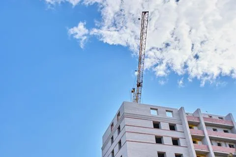 Construction site. Crane and multi-storey brick house against the blue sky. Stock Photos