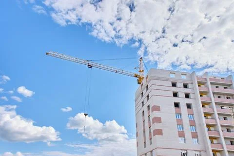 Construction site. Crane and multi-storey brick house against the blue sky. Stock Photos