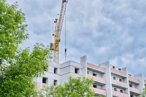 Construction site. Crane and multi-storey brick house against the blue sky. Stock Photos