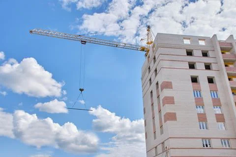 Construction site. Crane and multi-storey brick house against the blue sky. Stock Photos