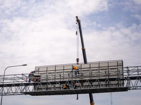 Construction site crane is lifting a led signboard for advertisement Stock Photos