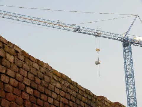 Construction site with cranes and a solid brick wall. Stock Photos