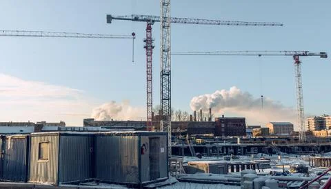 Construction site with cranes and work houses against blue sky Stock Photos