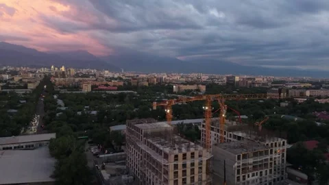 Construction site with cranes at dusk, city skyline and mountains visible Stock Footage 339124089