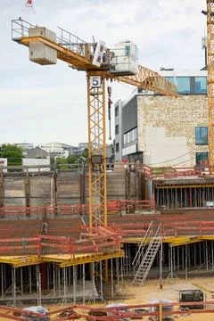Construction site with cranes, foundation pit, rebar, formwork, and partially Stock Photos