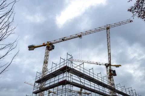 Construction site with cranes under cloudy sky Stock Photos