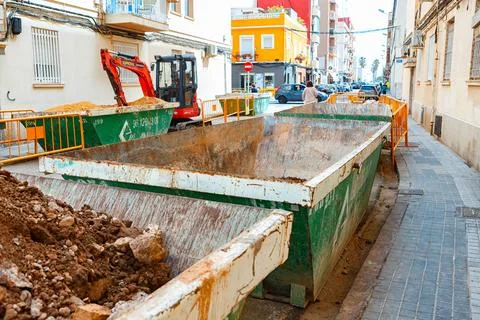 Construction Site With Debris Containers Filled With Dirt and Rubble on a Busy Stock Photos
