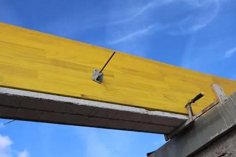 Construction site detail: yellow wooden beam and concrete structure against.. Stock Photos