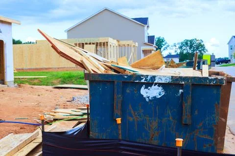 Construction site with dumpster filled with wood debris near new houses Stock Photos