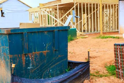 Construction site with dumpster, wooden framework visible in background Stock Photos