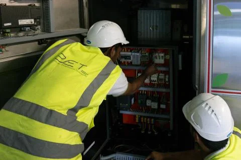 Construction site with engineers and workers fixing a machine in a factory Foto stock