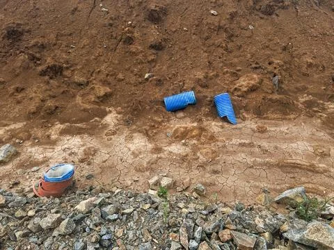 Construction site features blue drainage pipes and various materials on dry,  Stock Photos