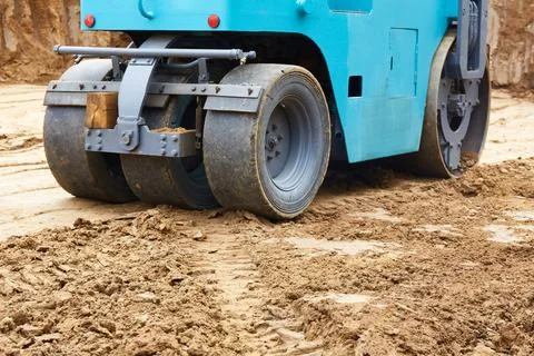 Construction site features a blue roller compacting earth on a freshly exca.. Stock Photos