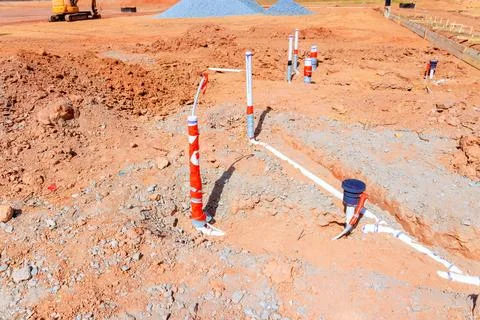 Construction site features newly installed plumbing pipes in sunlit area of Stock Photos