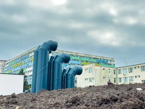 Construction site features pipes rising from soil near buildings under an o.. Foto stock