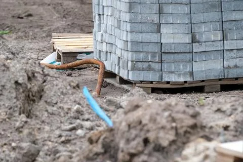 Construction site features stacked bricks near fresh earth and tools Stock Photos
